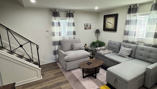 A modern living room with a grey sofa, a grey armchair, a wooden coffee table, and a striped rug. - Cozy and relaxing apartment with Free WiFi located in vibrant Atlanta. (Atlanta)