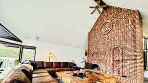 Una sala de estar moderna con un amplio sofá modular, una chimenea de ladrillo y una mesa de centro de madera.