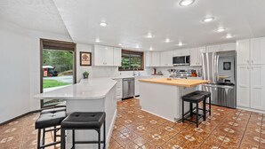 Una cocina moderna con armarios blancos, un refrigerador de acero inoxidable y una isla grande con taburetes.