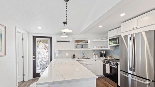 A modern kitchen with a large island, stainless steel appliances, and white cabinetry. - Anchor Inn 02 | 1BR/1BA Boca Grande, Chic Comfort (Boca Grande)