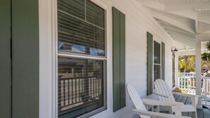 A porch with white chairs and a view of a backyard.