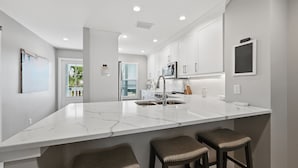 A modern kitchen with a large island, white cabinetry, and a view to the outside. - NEW LOW PRICE - Coastal BG North 82, a spacious 2-bed, 2-bath Boca Grande with stunning Gulf views (Boca Grande)