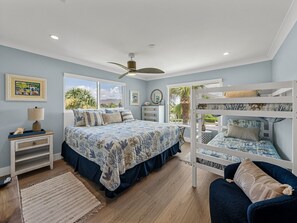 A bedroom with a large bed, bunk beds, a ceiling fan, and a view of the outdoors. - Experience luxury at Unit 84, a stunning 2-bedr 2-bath Gulf view condo in Boca Grande (Boca Grande)