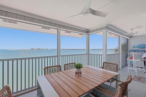 A balcony with a wooden table, chairs, and a potted plant. - Experience luxury at Unit 84, a stunning 2-bedr 2-bath Gulf view condo in Boca Grande (Boca Grande)
