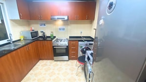 A kitchen with wooden cabinets, a microwave, a stove, an oven, and a washing machine.