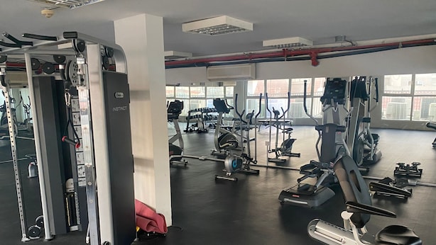A gym with various exercise equipment, large windows, and a mirrored wall.