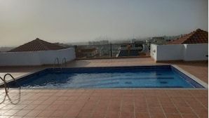 A rooftop swimming pool with a view of a city skyline.