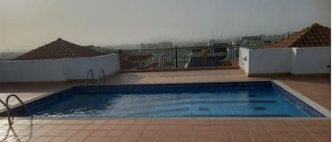 A rooftop swimming pool with a view of a city skyline.