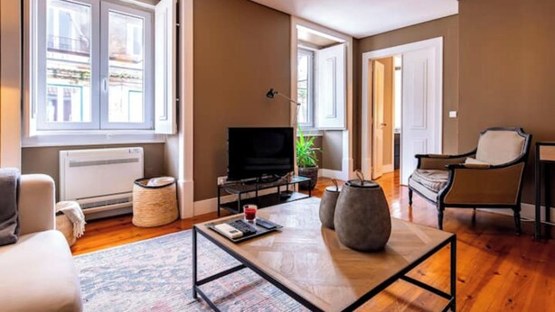 Ein Wohnzimmer mit einer Couch, einem Couchtisch, einem Fernseher und einer Pflanze.