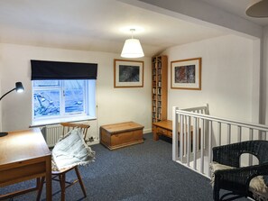 Una habitación con ventana, escritorio, silla, estantería y escalera.