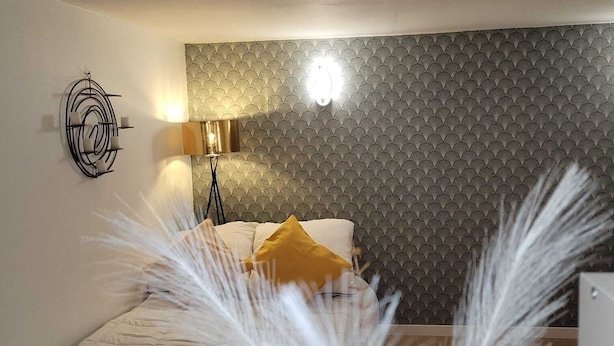 A bedroom with a bed, a wall-mounted lamp, and a decorative wall panel.