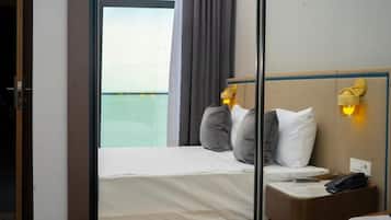A hotel room with a bed, bedside table, and a view of the sea.