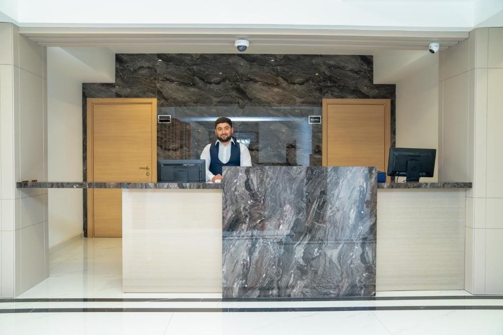 A reception desk with a marble front, wooden cabinets, and a security camera above.