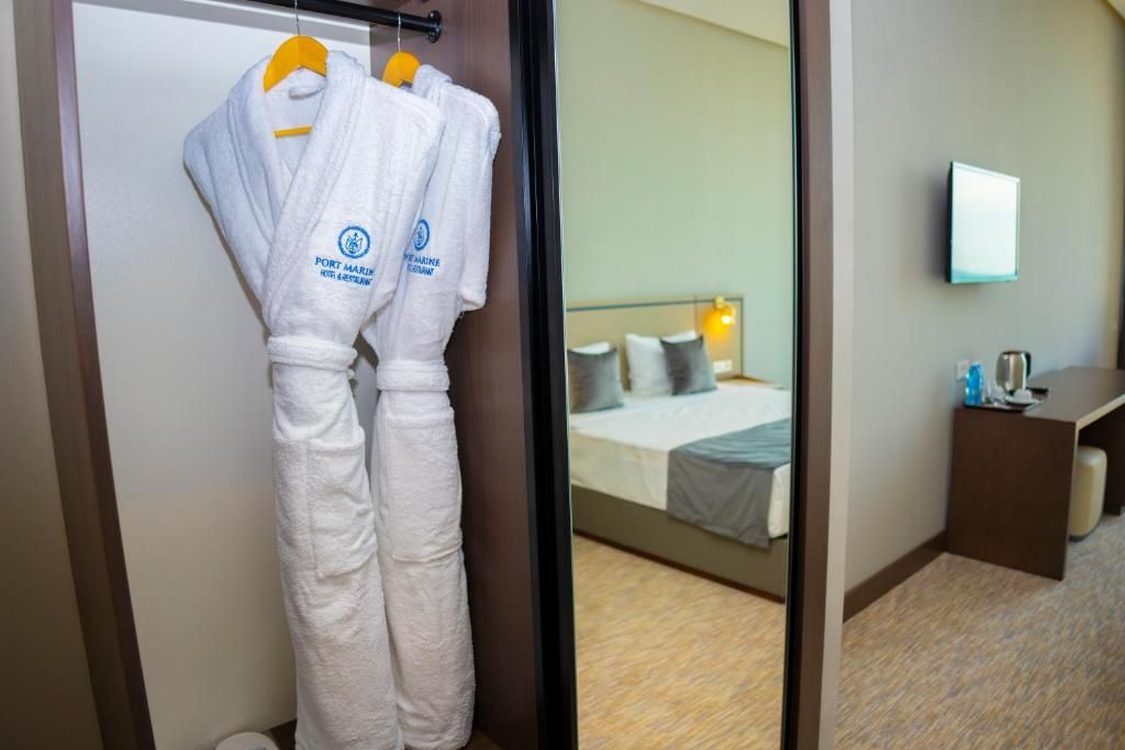 A hotel room with a bed, a bedside table, and a mirror on the wall.
