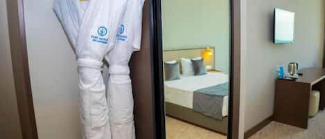 A hotel room with a bed, a bedside table, and a mirror on the wall.