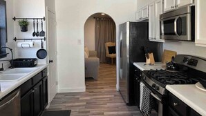 Una cocina moderna con electrodomésticos de acero inoxidable, armarios blancos y piso de madera.