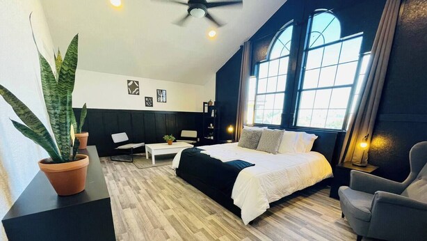 Una habitación de hotel moderna con una cama grande, un escritorio, una silla y una planta en maceta.