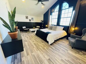 Une chambre d’hôtel moderne avec un grand lit, un bureau, une chaise et une plante en pot.