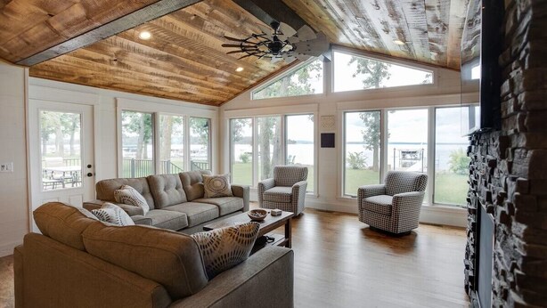 A spacious living room with a high ceiling, large windows, and a view of the outdoors. - Gull Lake Cabin + Bunkhouse with Sandy Beach & Pontoon/Jet Ski availability! (Nisswa)