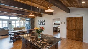 A spacious kitchen with a large island, wooden beams, and pendant lighting. - Gull Lake Cabin + Bunkhouse with Sandy Beach & Pontoon/Jet Ski availability! (Nisswa)