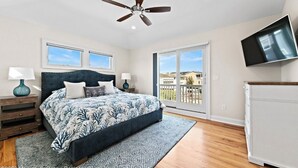 A bedroom with a bed, two bedside tables, a ceiling fan, a TV, and a balcony with a view. - Immaculate Pool/Elevator 5 bedroom, 4 bath home w/outdoor living space/fire pit  (Harvey Cedars)