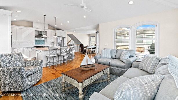 A spacious living area with a kitchen, dining area, and a staircase leading to another level. - Immaculate Pool/Elevator 5 bedroom, 4 bath home w/outdoor living space/fire pit  (Harvey Cedars)