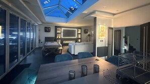 Ein modernes Wohnzimmer mit Oberlicht, Billardtisch und Essbereich.