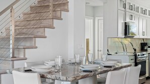 A modern kitchen with white cabinets, a marble countertop, and a stainless steel range hood.