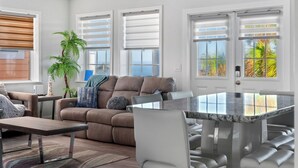 A modern living room with a brown sofa, a glass dining table, and a potted plant.
