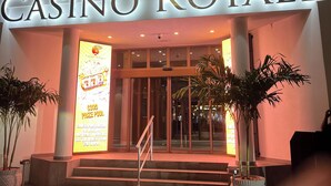 La entrada al Casino Royale, con letreros iluminados, una puerta de cristal y una escalera que conduce a la entrada.
