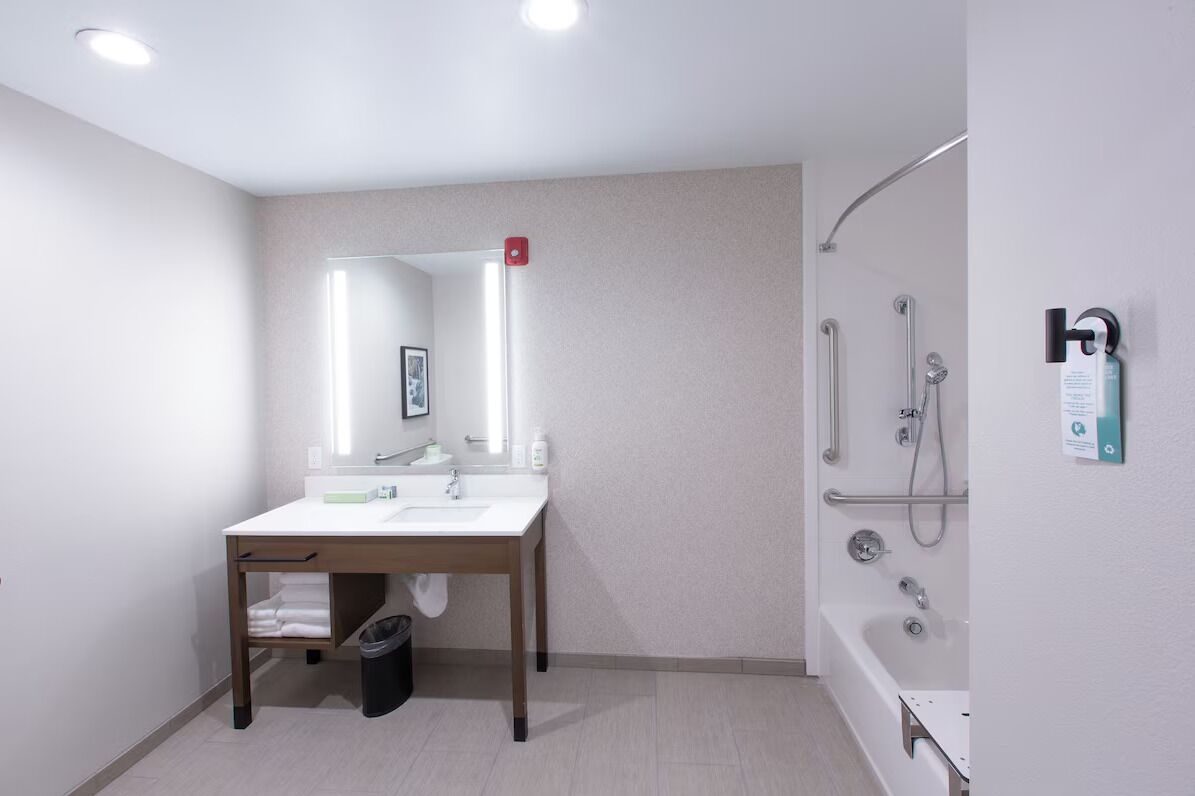 A modern bathroom with a white sink, mirror, and shower.