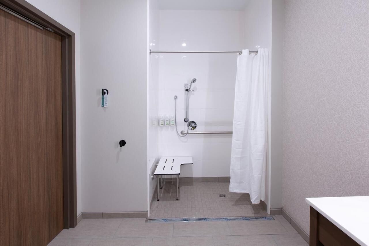A bathroom with a shower, a toilet, and a small bench.
