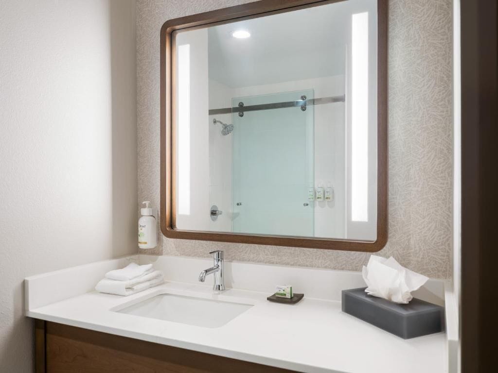 A bathroom with a white sink, a mirror, and a glass shower enclosure.