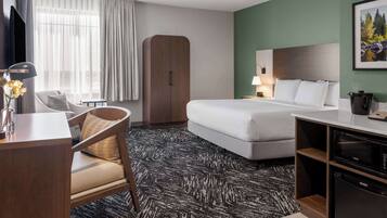 Habitación de hotel con cama, escritorio, silla, armario, televisor y microondas.