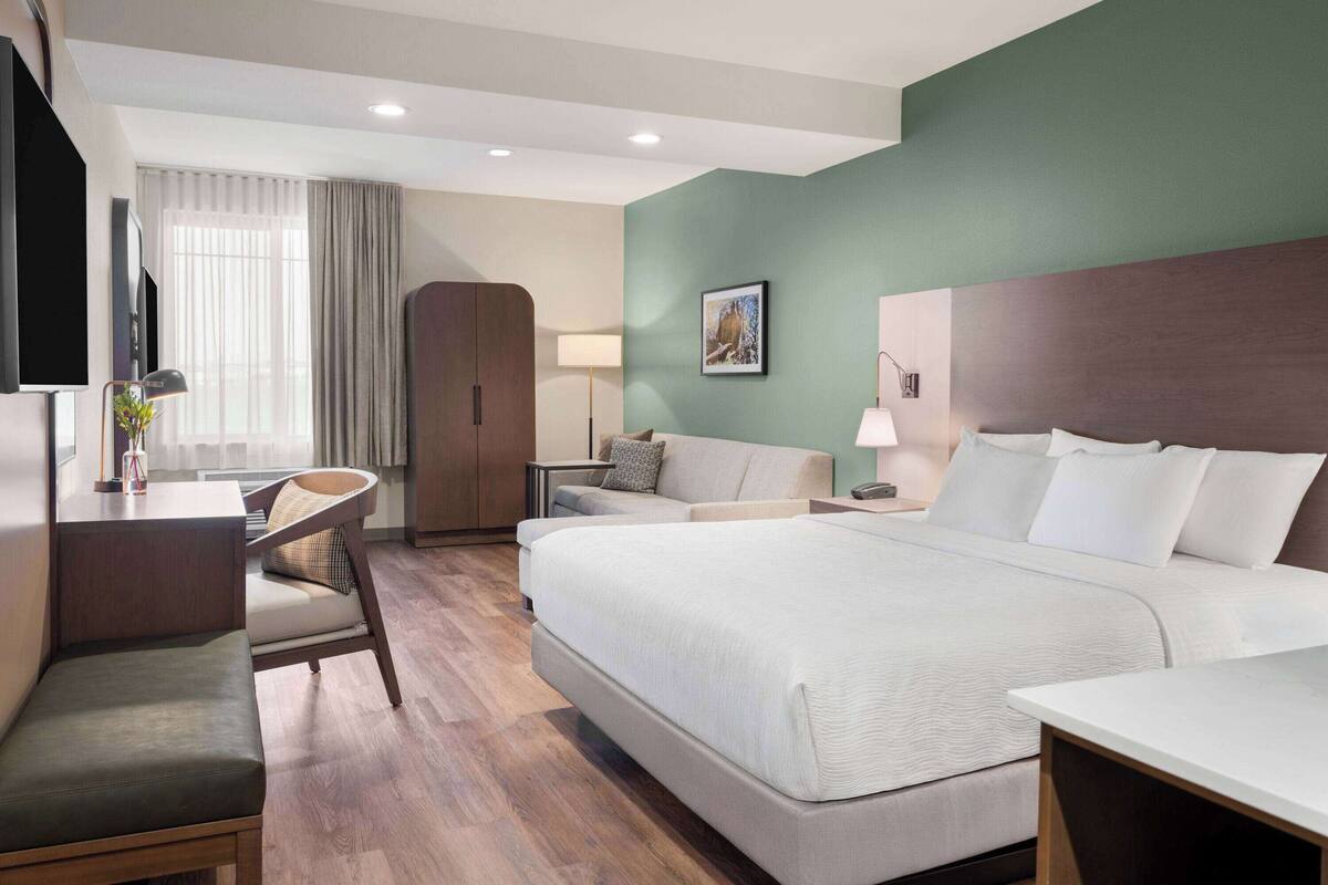 Une chambre d’hôtel moderne équipée d’un grand lit, d’un bureau, d’une chaise, d’une table de chevet et d’un téléviseur.
