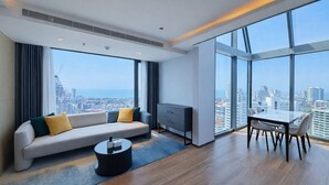 Una moderna camera d'albergo con divano, tavolo da pranzo e vista sulla città.