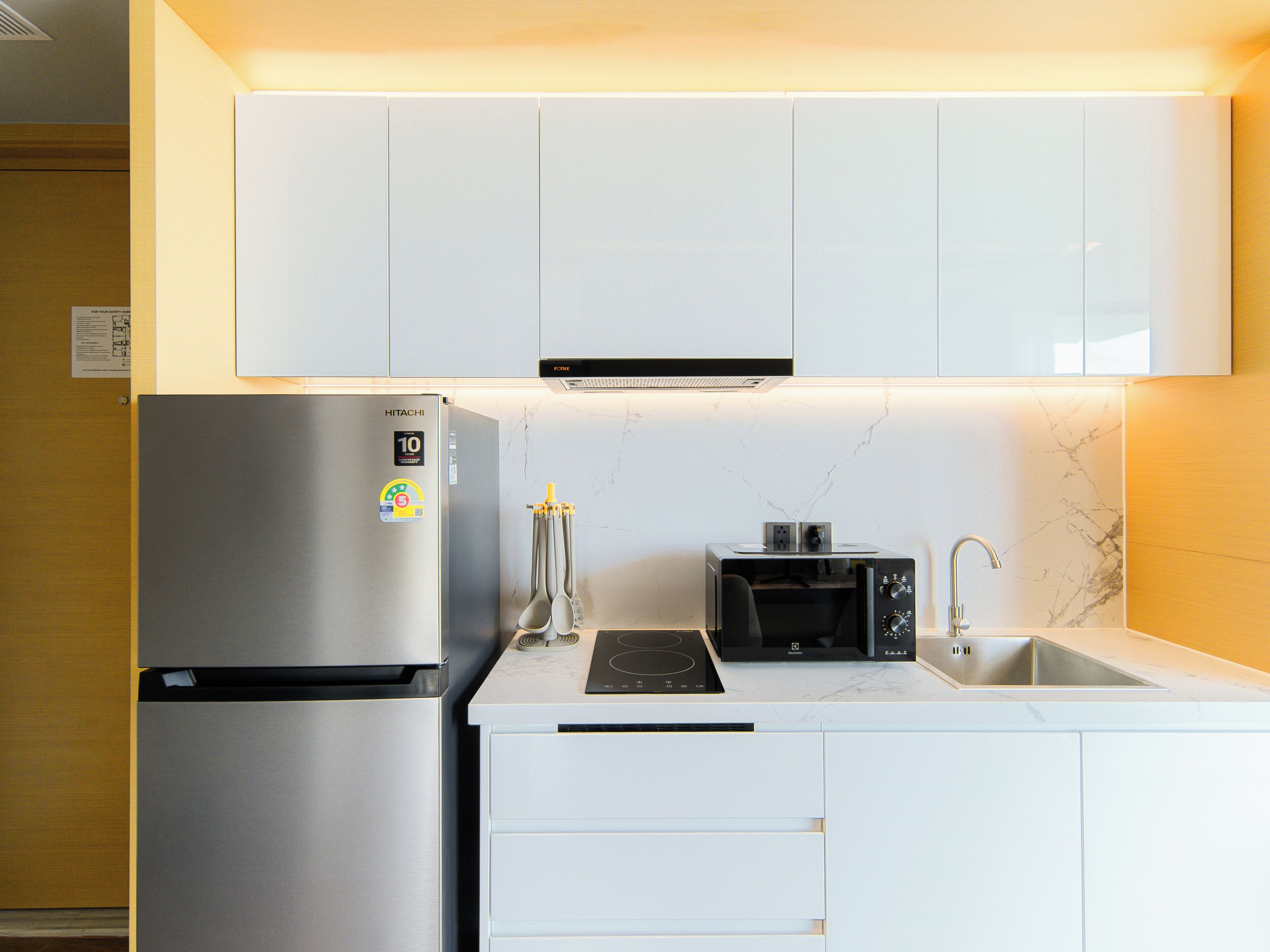 A modern kitchen with white cabinetry, a stainless steel refrigerator, a built-in microwave, and a gas stove.