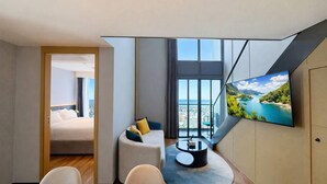 Una camera d'albergo moderna con un letto, un divano, un tavolo da pranzo e una TV a parete.