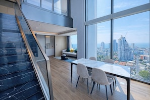 Un intérieur moderne comprenant un coin repas, un escalier et une vue sur la ville.