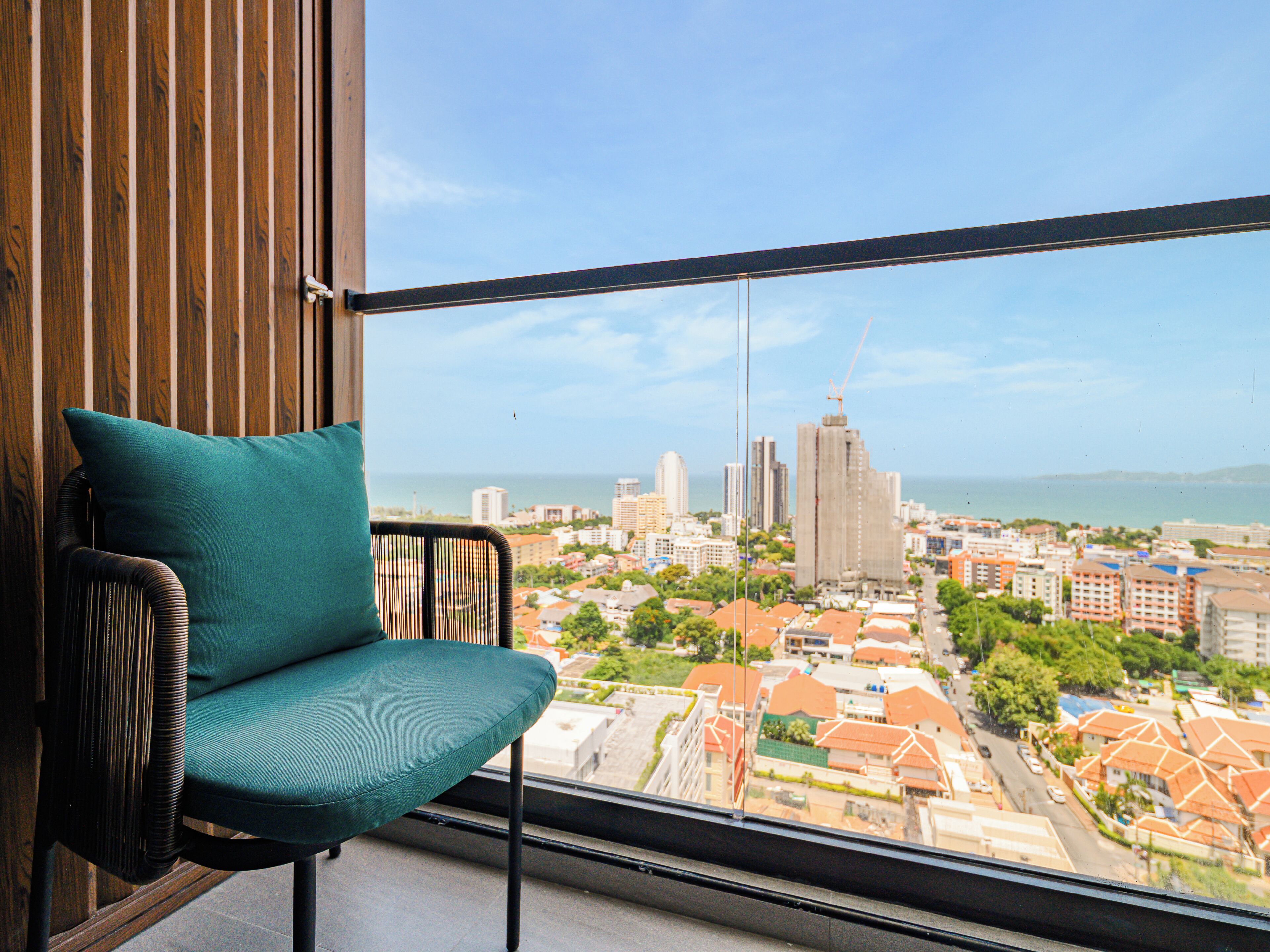 A balcony with a view of a cityscape, including buildings and a body of water.