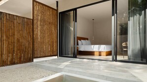 Une chambre moderne dotée d’un grand lit, de portes-fenêtres coulissantes donnant sur un balcon et d’un petit espace extérieur avec un jacuzzi.
