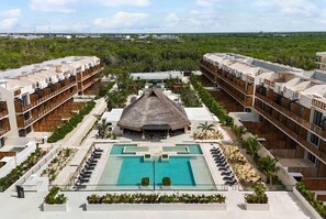A resort with multiple-story buildings, a central pool, and a thatched-roof structure. - Wyndham Residences Tulum (Tulum)