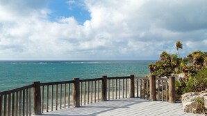 A wooden deck with a railing overlooking a beach and ocean. - Wyndham Residences Tulum (Tulum)