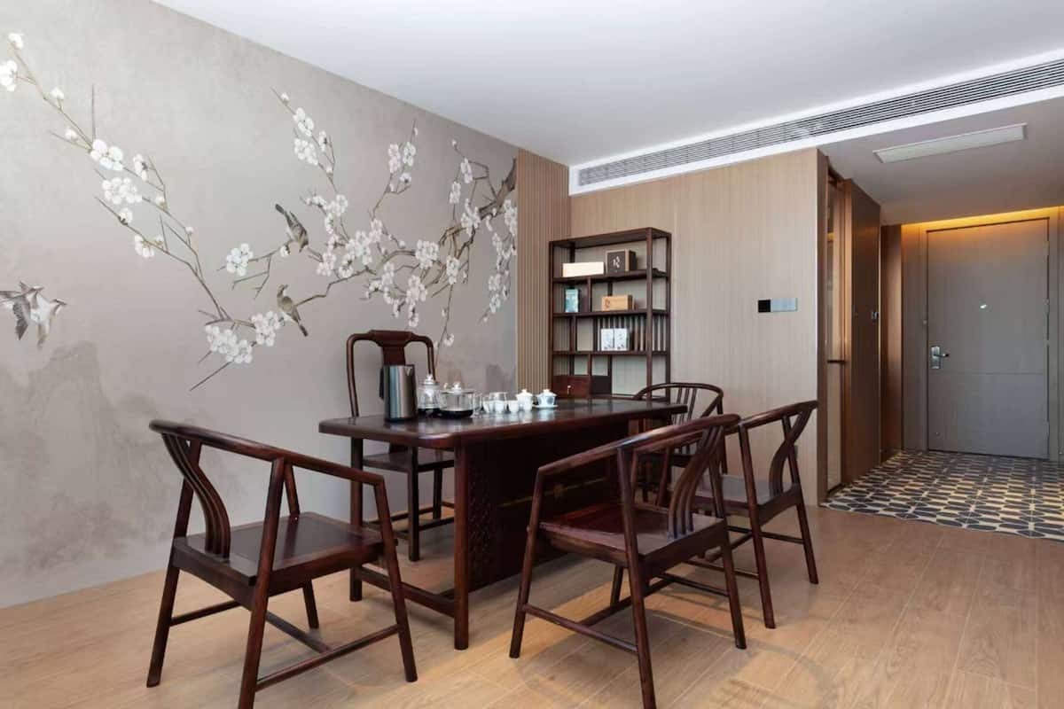 Ein Essbereich mit einem Holztisch, Stühlen, einem Bücherregal und einer Wand mit einer floralen Wandmalerei.
