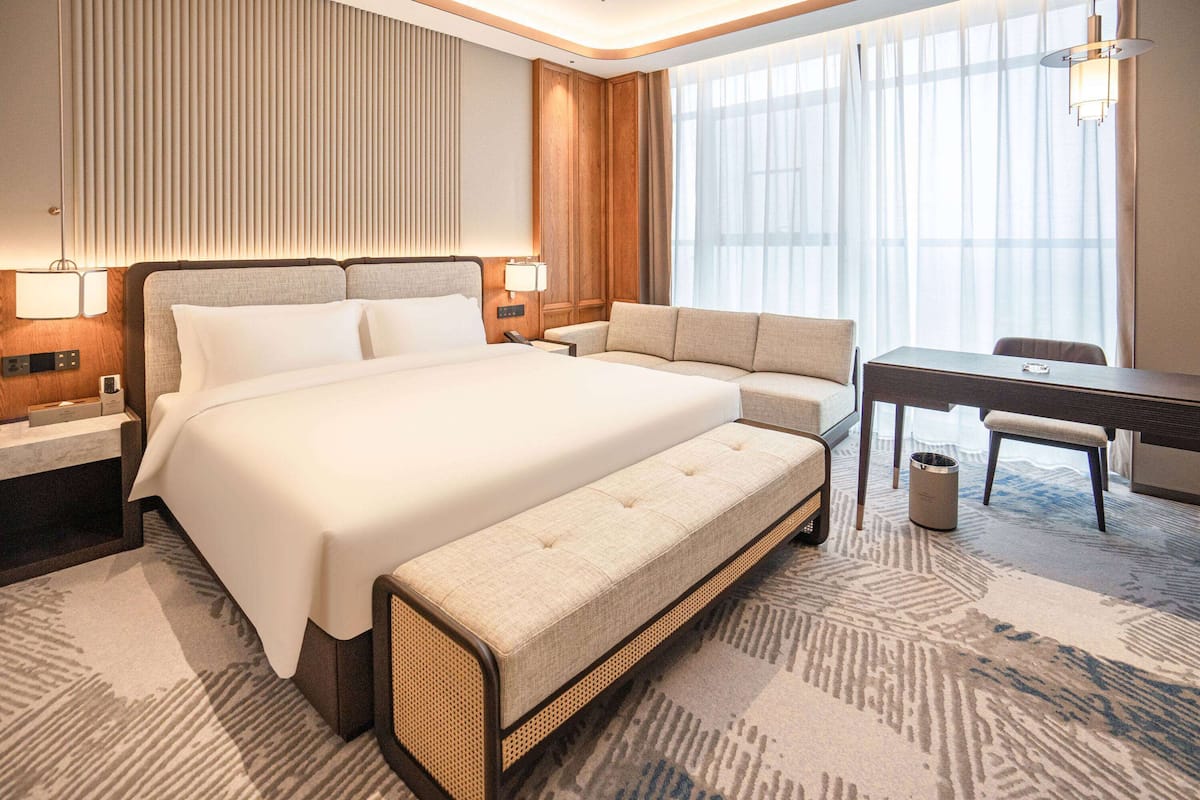 Une chambre d’hôtel avec un grand lit, un canapé, un bureau et une poubelle.