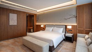 Ein modernes Hotelzimmer mit einem großen Bett, einer Sitzecke und einem Holzschrank.