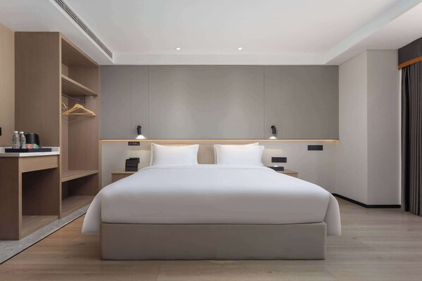 A modern hotel room with a large bed, a desk with a chair, and a wardrobe. - Microtel By Wyndham Nanchang (Nanchang)