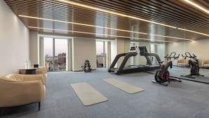 A modern gym with exercise equipment, a treadmill, stationary bikes, and a mirror wall.