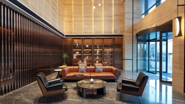 A modern lobby with a leather sofa, a coffee table, and a decorative wall with shelves.