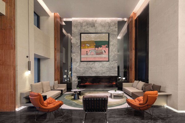 A modern lobby with a fireplace, sofas, and a coffee table. - Ramada By Wyndham Zhuhai Xiangzhou (Zhuhai)